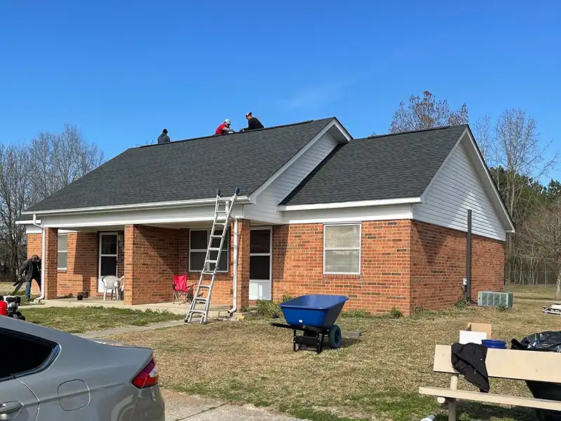 Square1 Construction LLC crew members installing new black shingles on a small home