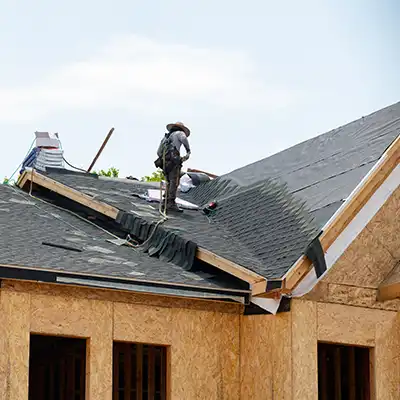 Roofer installing new gray shingles on a new construction home